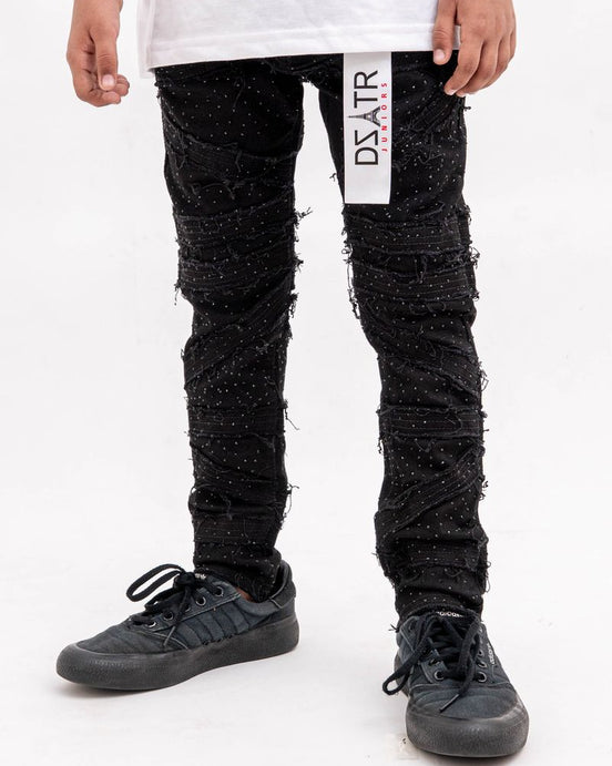 Person wearing black distressed jeans with a visible brand label on a white background