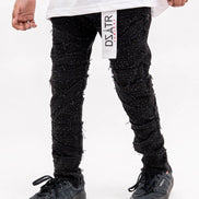 Person wearing black textured pants with a visible brand label on a white background