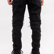 Person wearing black distressed jeans on a white background
