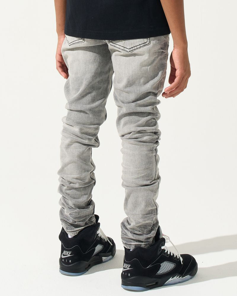 Person wearing gray jeans and black sneakers on a white background