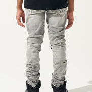 Person wearing light gray jeans and black Nike sneakers on a white background