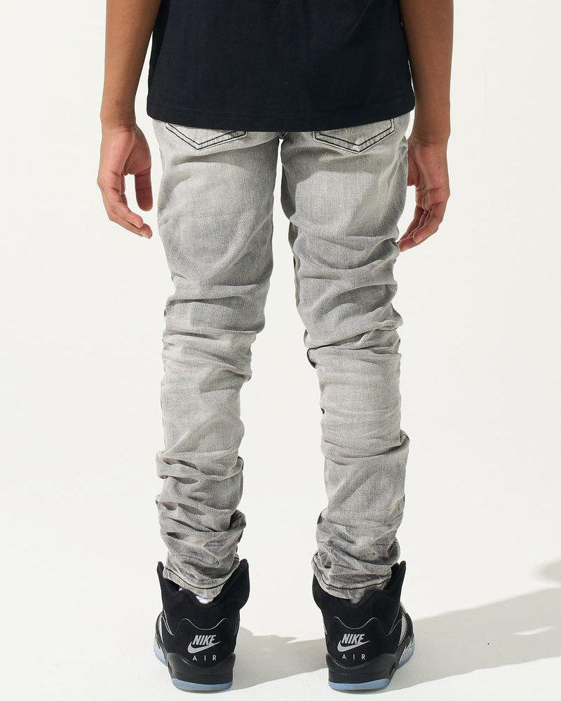 Person wearing light gray jeans and black Nike sneakers on a white background