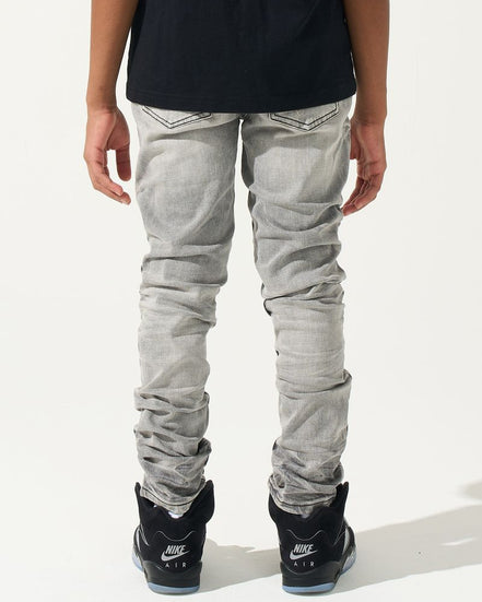 Person wearing light gray jeans and black Nike sneakers on a white background