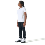 A person standing in profile wearing a plain white short-sleeve T-shirt, black pants, and white sneakers against a clean white studio background.