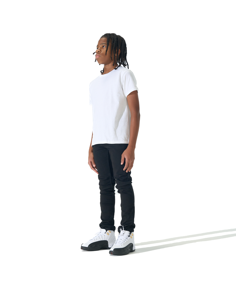 A person standing in profile wearing a plain white short-sleeve T-shirt, black pants, and white sneakers against a clean white studio background.