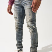 Person wearing distressed gray jeans and black and white sneakers on a white background
