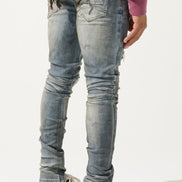 Person wearing light blue distressed jeans and black and white shoes on a plain background