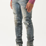Person wearing distressed gray jeans and black and white sneakers on a white background