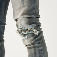 Close-up of distressed jeans with embellishments on a white background