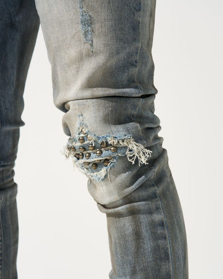 Close-up of distressed jeans with embellishments on a white background