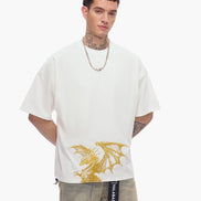 Man wearing a white t-shirt with a gold dragon design on a plain background