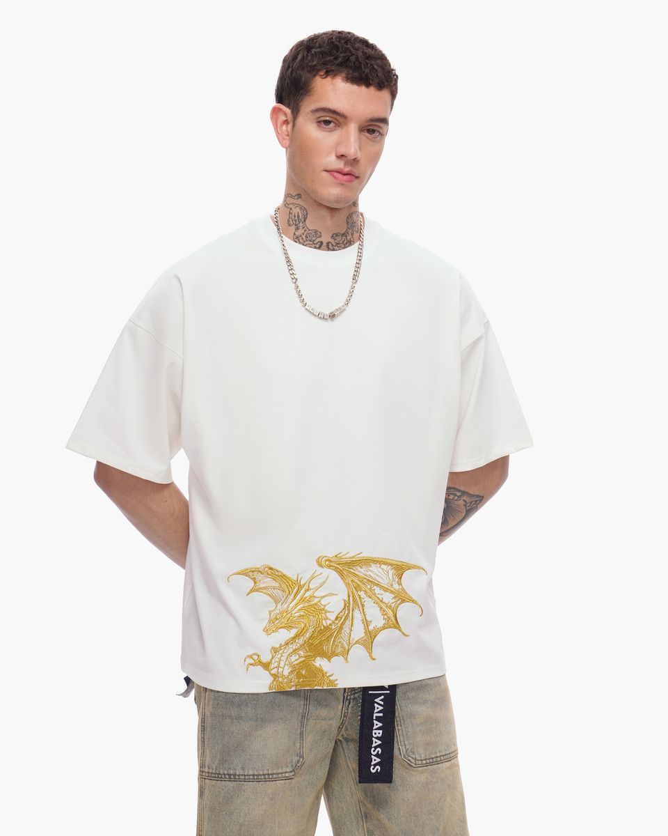 Man wearing a white t-shirt with a gold dragon design on a plain background