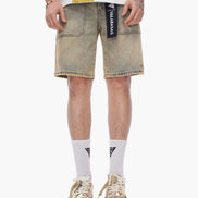Person wearing light-colored denim shorts with a brand logo, white socks, and brown shoes on a white background.