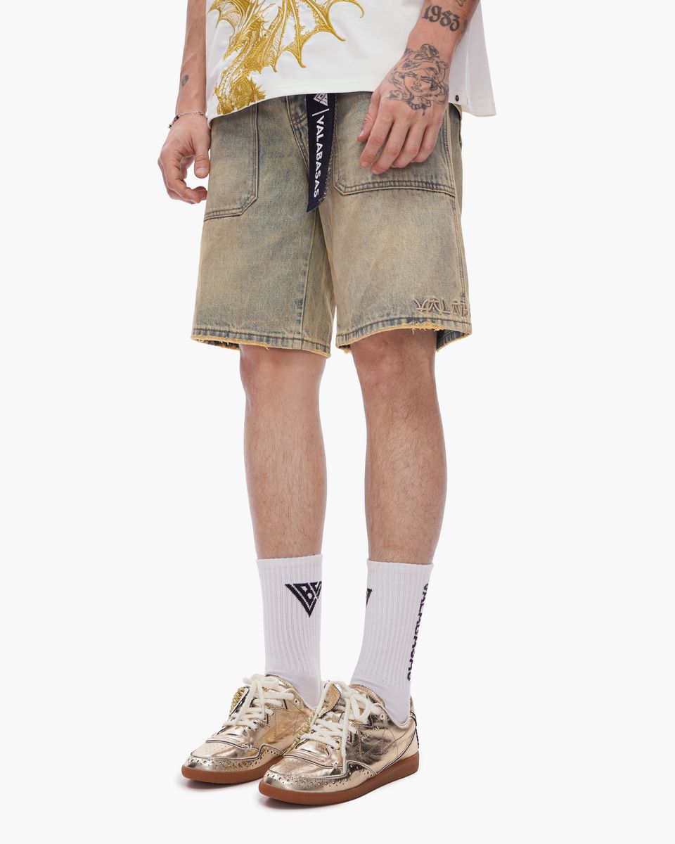 Person wearing beige denim shorts, white socks with a logo, and brown sneakers on a white background