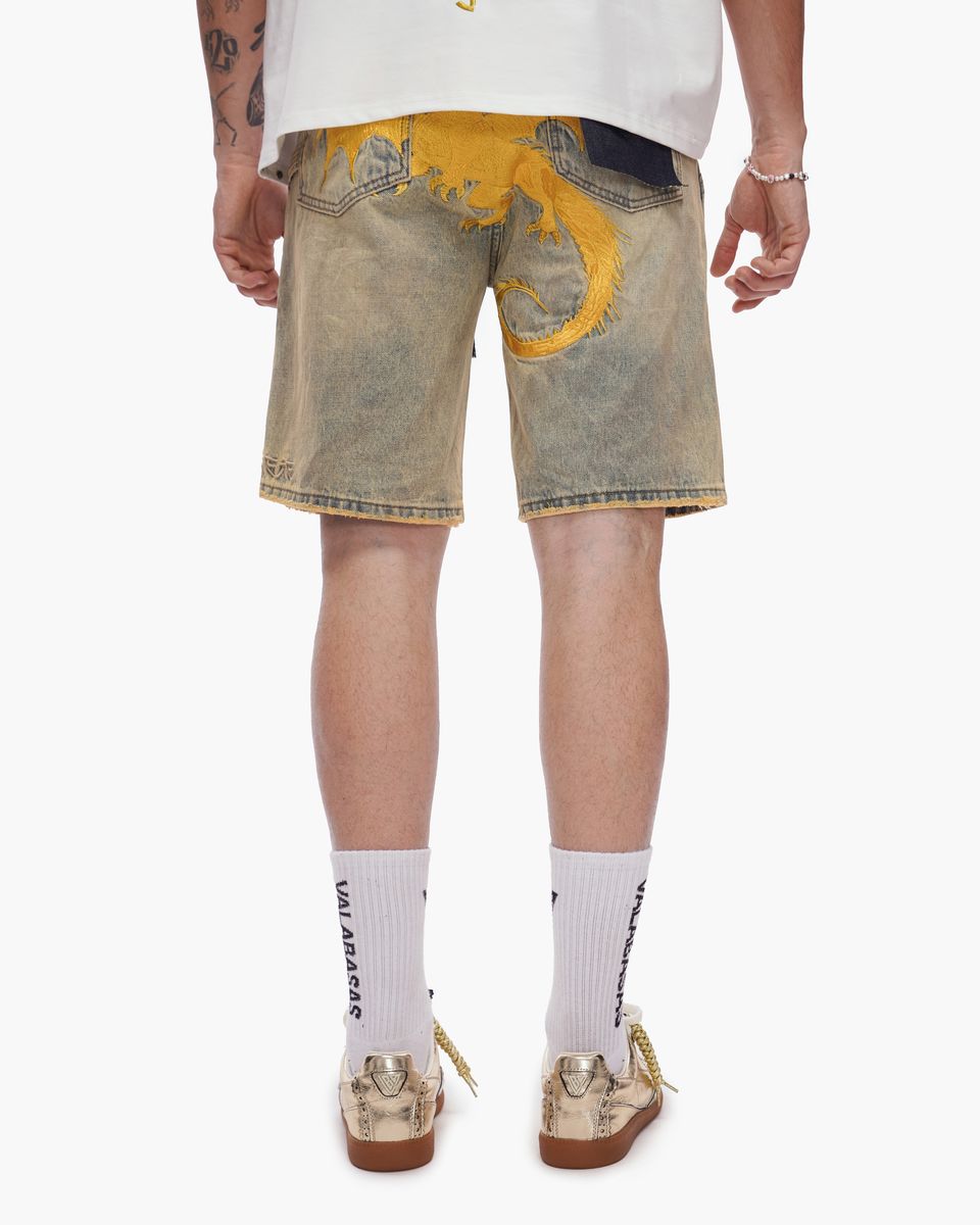 Person wearing light-colored denim shorts with yellow accents on a white background