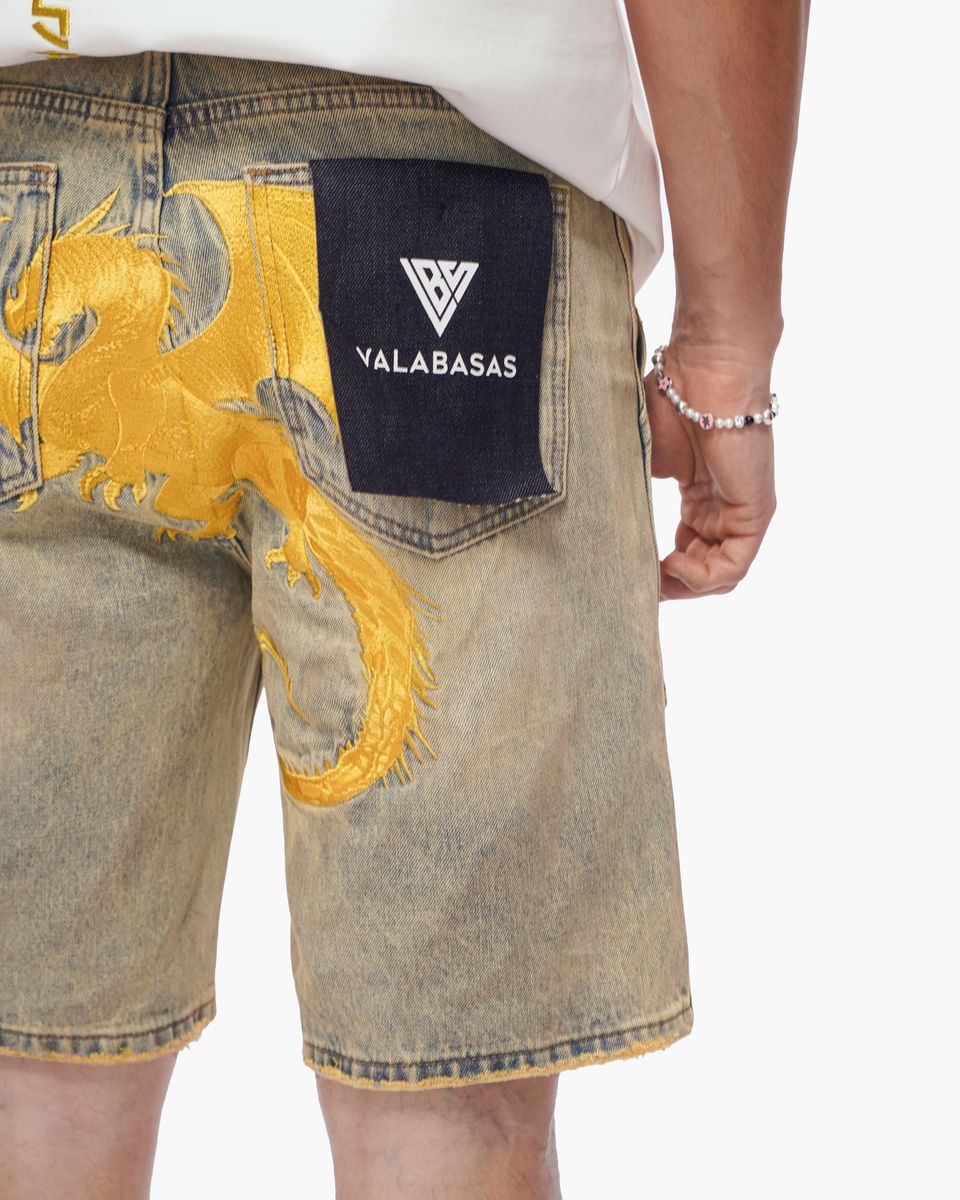 Denim shorts with a gold dragon design and Valabasas logo on a white background