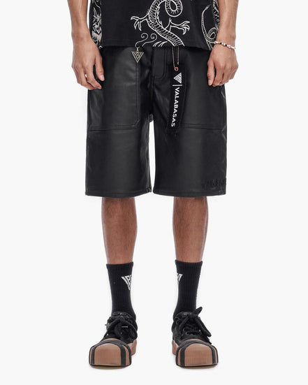 Person wearing black leather shorts with visible branding on a white background