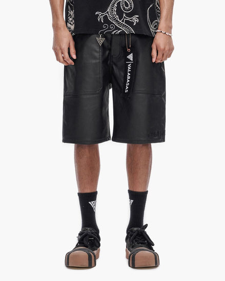 Person wearing black leather shorts with visible branding on a white background