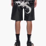 Person wearing black shorts with white dragon design on a white background