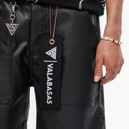 Black leather shorts with a visible brand tag and accessories on a white background