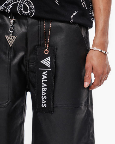 Black leather shorts with a visible brand tag and accessories on a white background