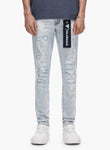 Person wearing light blue distressed jeans with a brand logo on a white background