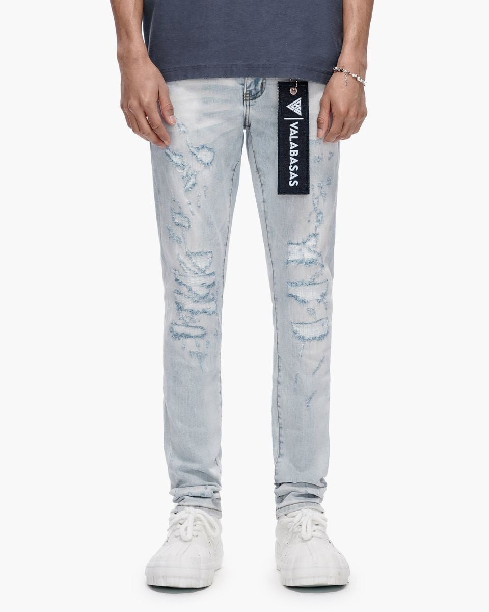Person wearing light blue distressed jeans with a brand logo on a white background