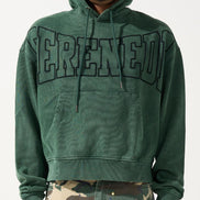 Person wearing a green hoodie with 'SERENEDE' printed on it, standing against a white background.
