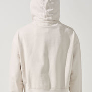 Person wearing a beige hoodie with the back facing the camera on a white background