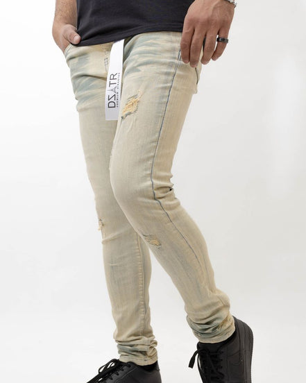 Person wearing beige distressed jeans with a visible brand label on a white background