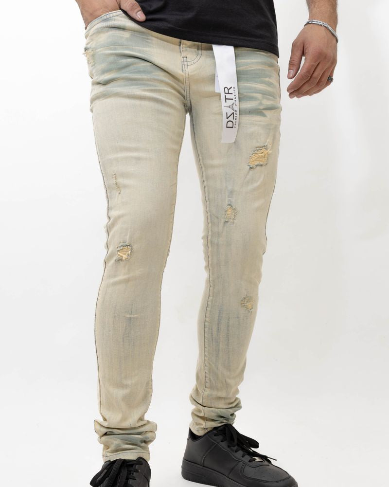Beige distressed jeans worn by a person on a white background