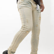 Person wearing light beige distressed jeans with black sneakers on a white background