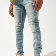 Person wearing light blue distressed jeans and colorful sneakers on a white background