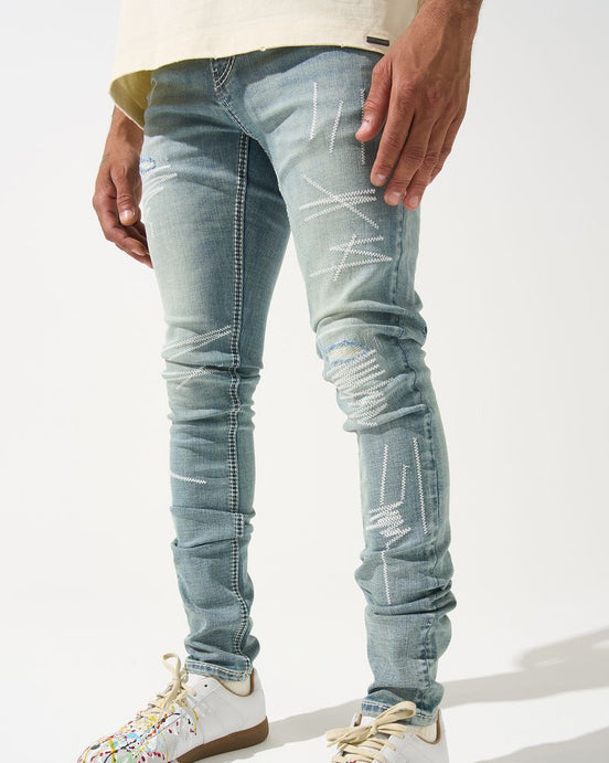 Person wearing light blue distressed jeans and colorful sneakers on a white background