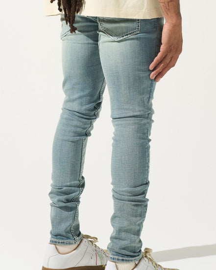 Person wearing light blue jeans and white sneakers on a white background