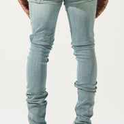 Person wearing light blue jeans and white shoes on a plain background