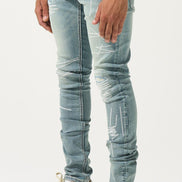 Person wearing light blue distressed jeans and white sneakers with brown soles on a white background