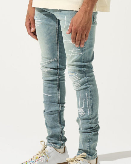Person wearing light blue distressed jeans and white sneakers with brown soles on a white background