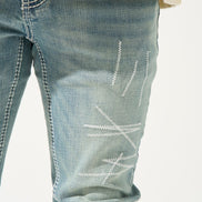 Close-up of blue jeans with white stitching on a white background