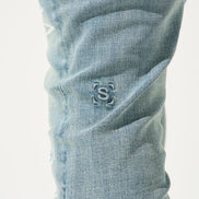 Close-up of light blue denim jeans with a brand logo on the pocket.