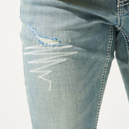 Close-up of distressed blue jeans on a white background