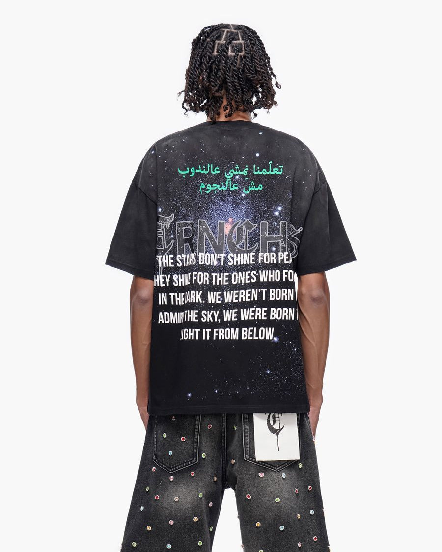 Person wearing a black t-shirt with text on the back, standing against a white background