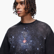 Person wearing a black t-shirt with a galaxy design and logo on a white background