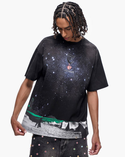 Person wearing a black t-shirt with a galaxy design on a white background