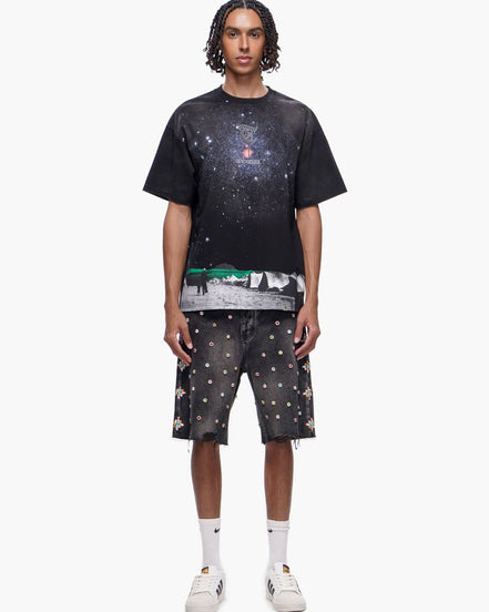 Person wearing a black t-shirt with space-themed design and matching shorts on a white background