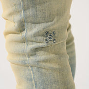 Close-up of a light blue denim pocket with a brand logo on a white background