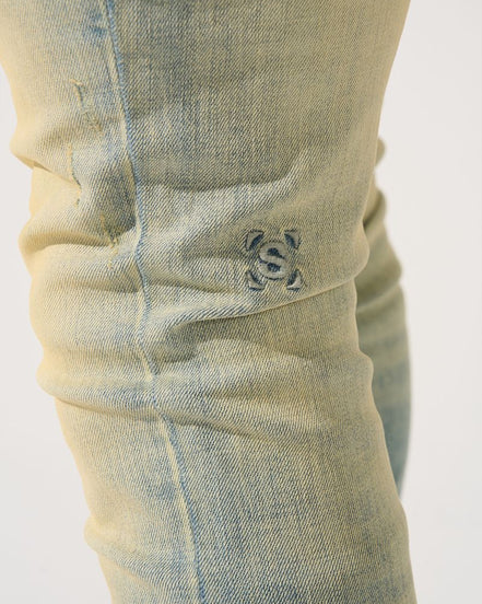 Close-up of a light blue denim pocket with a brand logo on a white background