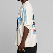 Person wearing a white t-shirt with blue floral patterns on a gray background