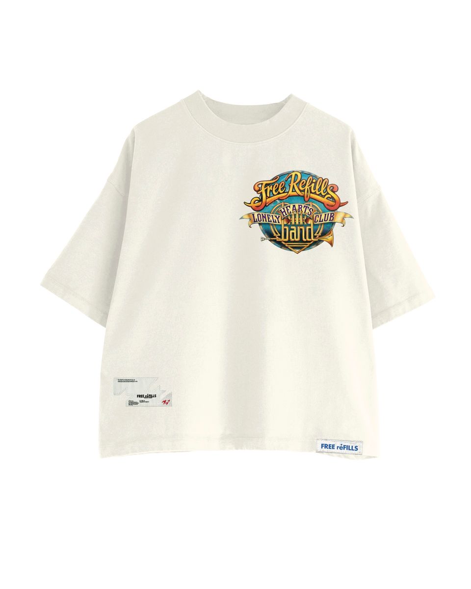 An oversized off-white t-shirt featuring a colorful graphic on the chest, with a small 'FREE-REFILLS' brand label on the bottom right hem and a small white tag on the bottom left hem, displayed against a solid white background.