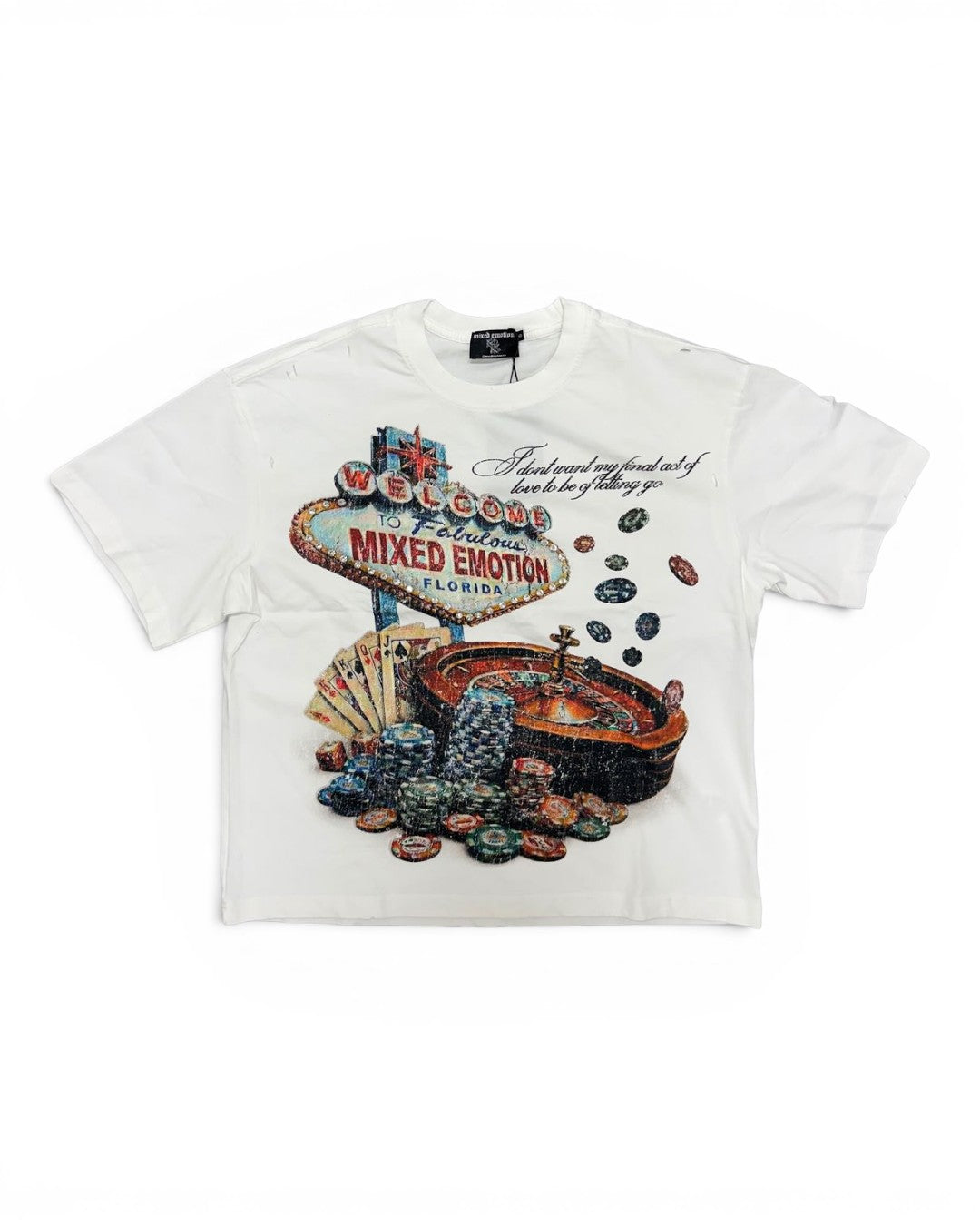 A white short-sleeve graphic t-shirt featuring a Las Vegas 'Welcome to Fabulous City of Mixed Emotion' sign surrounded by poker chips and a roulette wheel.